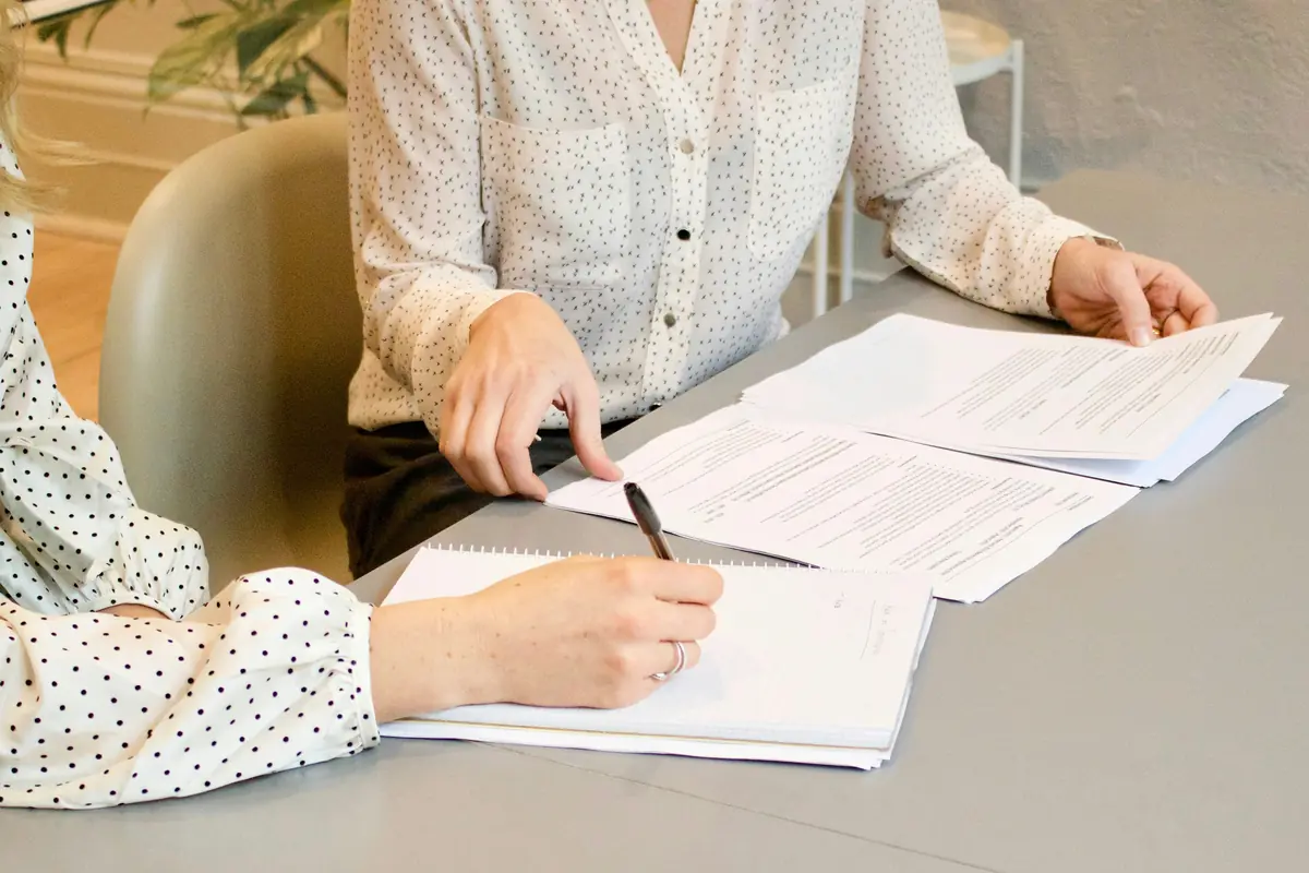 Deux personnes examinent des documents et prennent des notes